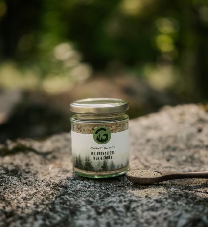 Pot de sel aromatique sauvage et cuillère de bois sur une pierre