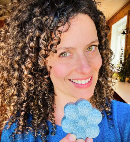 Ariane Paré-Le Gal sourit en tenant un produit bleu en forme de fleur dans une pièce lumineuse.