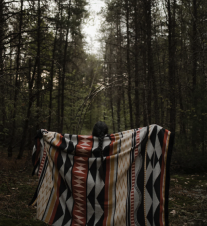 Couverture réversible à motifs géométriques tenue sur un sentier forestier