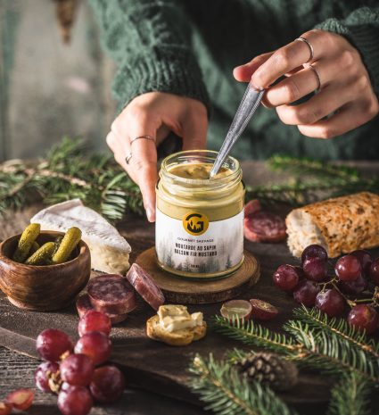 Pot de moutarde au sapin remué à la cuillère sur une table en bois