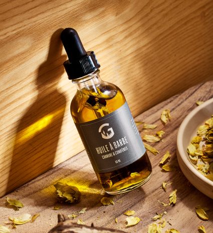 Huile à barbe en bouteille compte-gouttes sur une planche de bois
