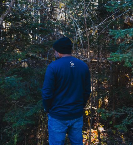 Homme portant un coton ouaté bleu dans une forêt de conifères