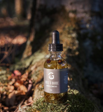 Huile à barbe et sérum visage dans une bouteille sur une souche moussue