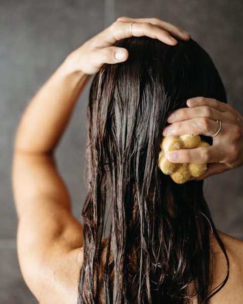 Personne se lavant les cheveux avec un savon solide sous la douche