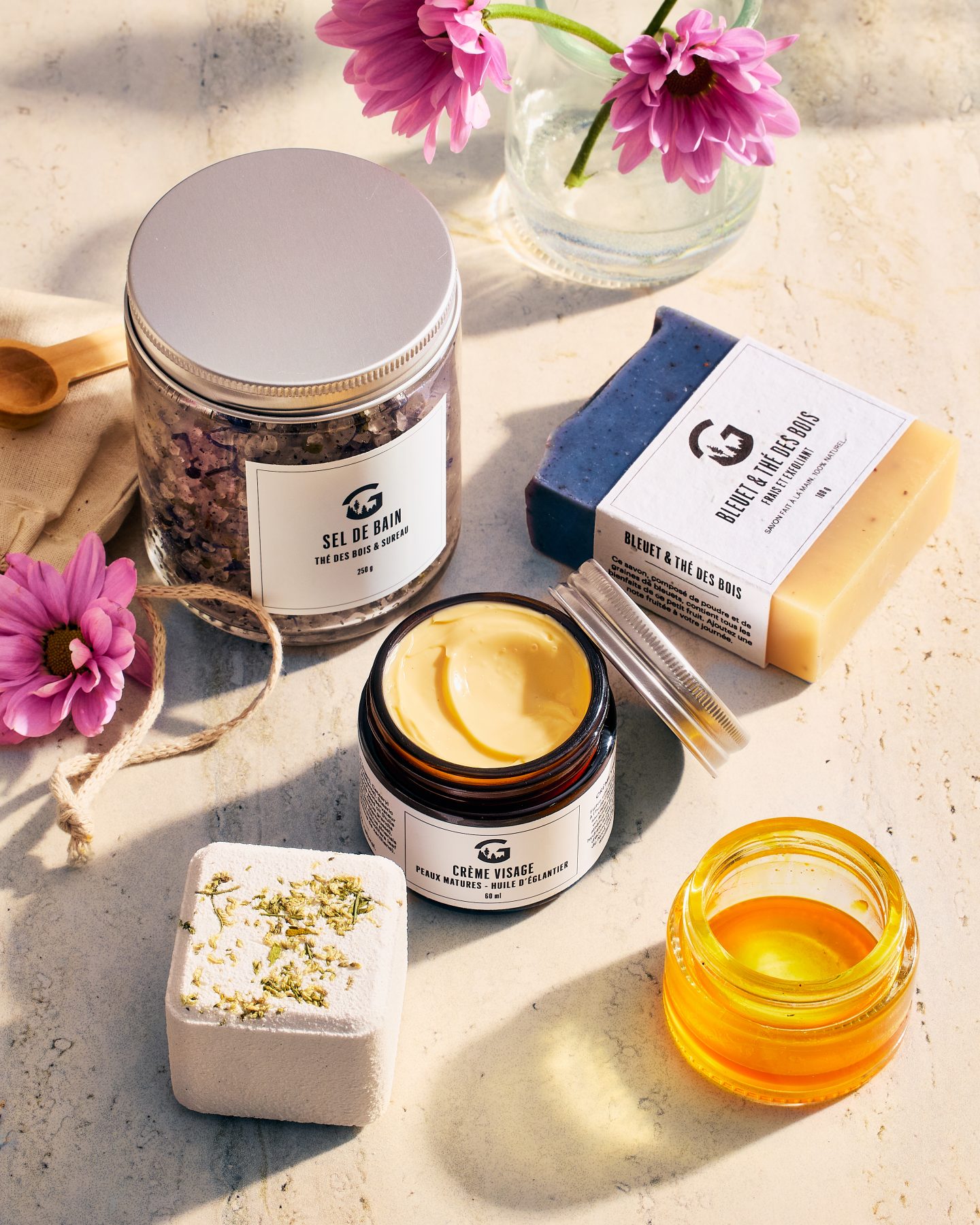 pot de crème visage, sel de bain et savon sur une surface claire