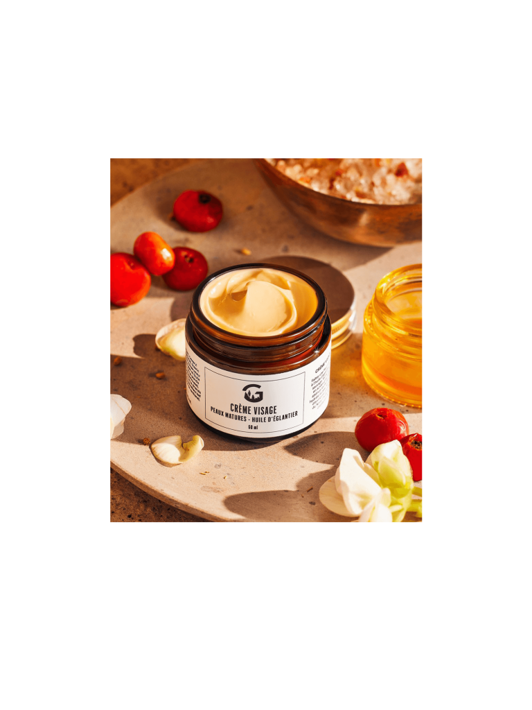 Pot ouvert de crème visage à l’huile d’églantier sur une surface beige