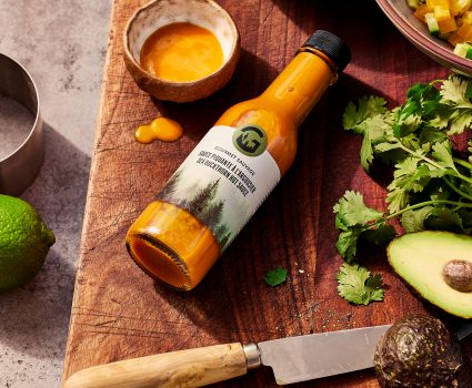 Bouteille de sauce piquante à l’argousier sur une planche à découper