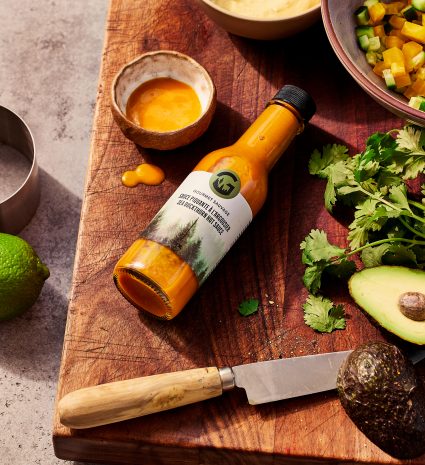 Bouteille de sauce piquante à l’argousier sur une planche à découper