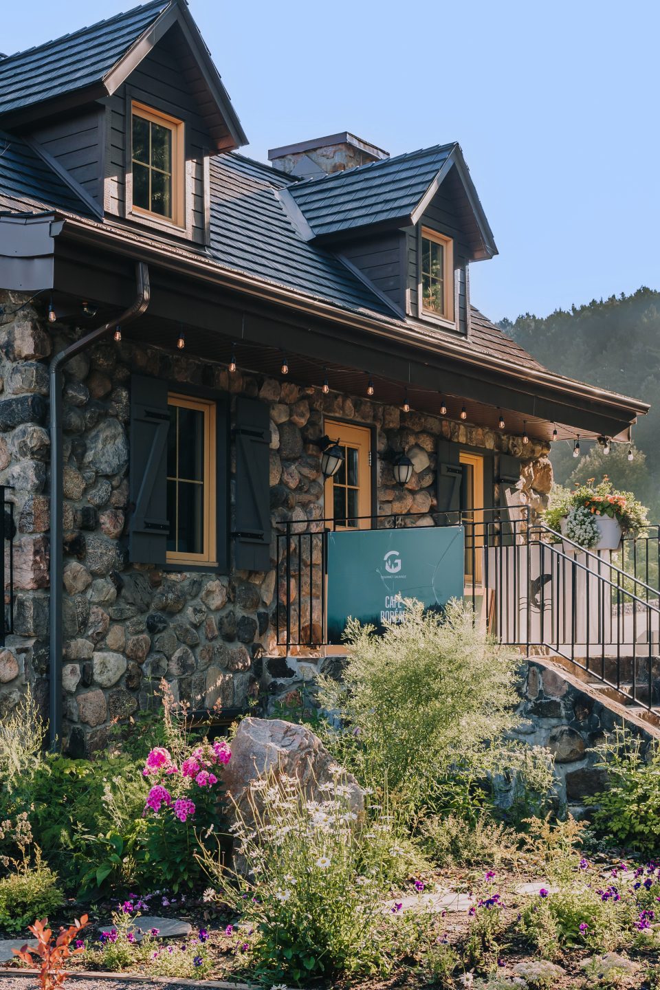 maison en pierre avec jardin fleuri et panneau bleu