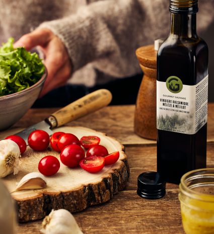 Bouteille de vinaigre balsamique mélèze et mélilot avec tomates sur une planche