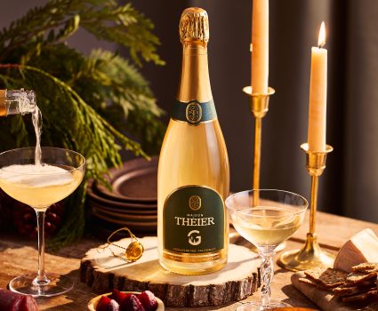 Bouteille de vin mousseux sur planche en bois avec verres et bougies