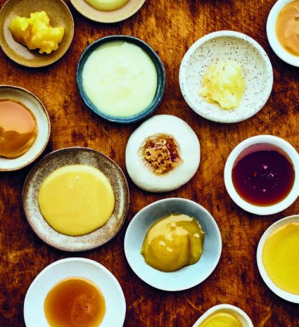 Échantillons de miel dans des bols et assiettes sur une planche de bois