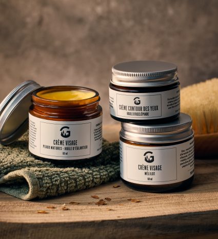 Trois pots de crème visage et contour des yeux sur une planche de bois