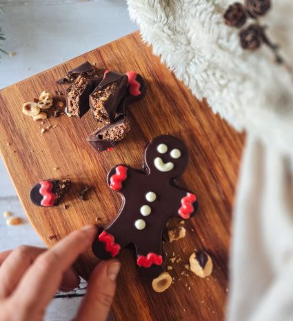 Bonhomme en chocolat sur planche en bois avec morceaux de chocolat et noisettes