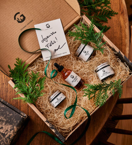 Coffret de pots et flacons avec branches de conifère sur une table en bois