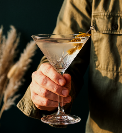 Verre à martini avec garniture végétale jaune tenu à la main