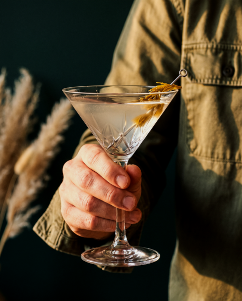 Verre à martini avec garniture végétale jaune tenu à la main